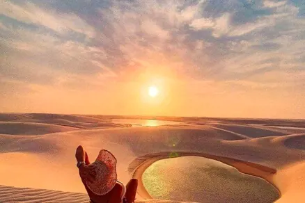 Pôr do sol sobre as dunas, com uma lagoa ao fundo